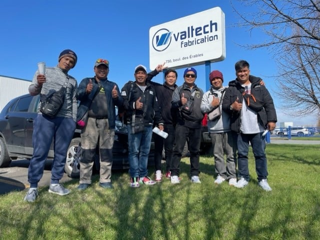 Filipino workers in front of the Valtech Vabrication sign.